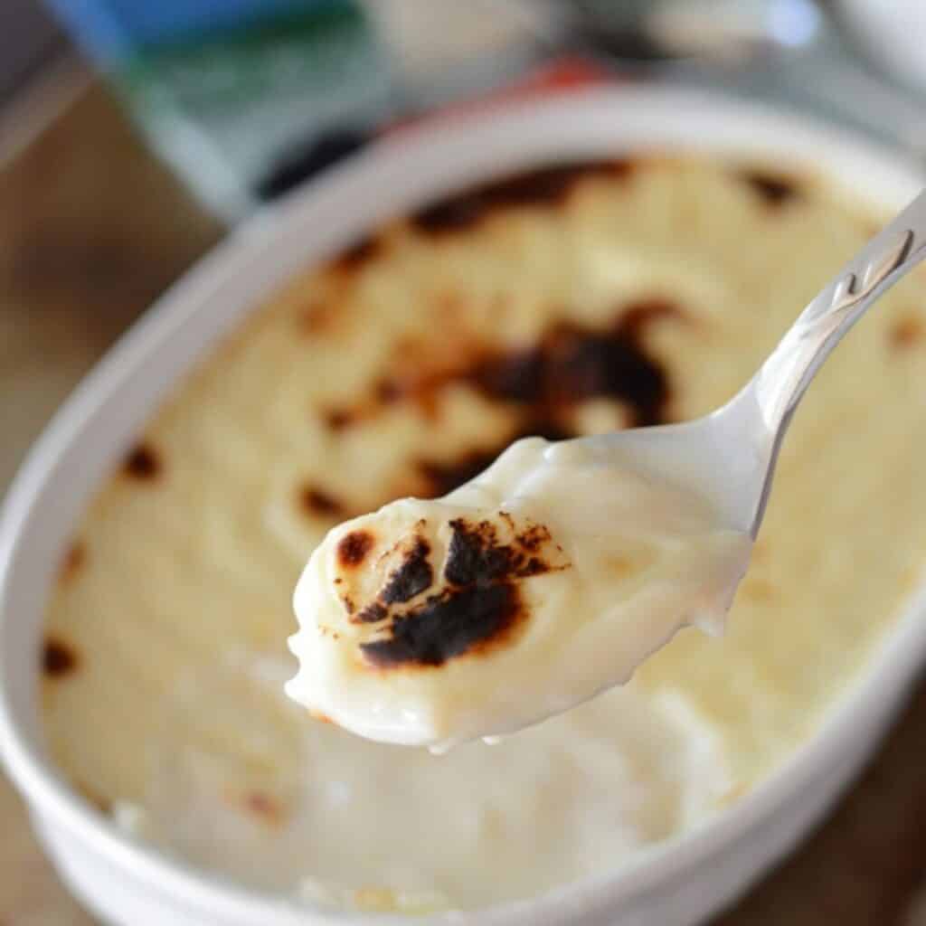 A spoon scooping some rice pudding out of an oven dish.