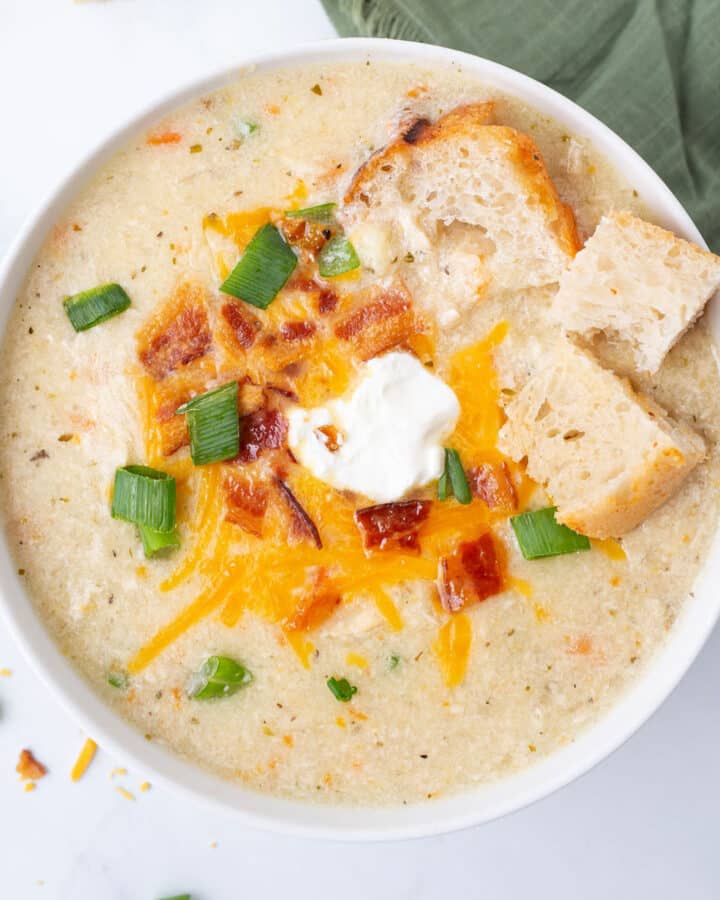 A top view pf a white bowl of potato soup.