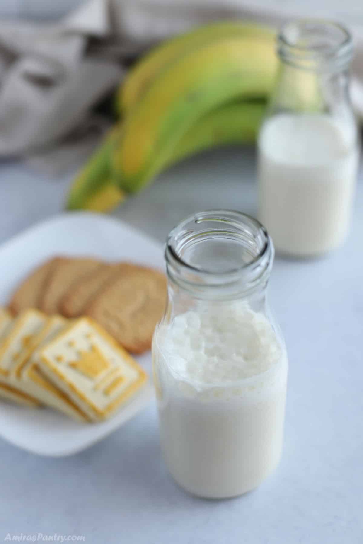 Bottles of banana milk with cookies on the side.