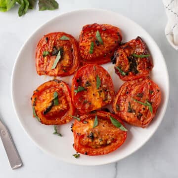 A top view of roasted tomatoes on a white plate.