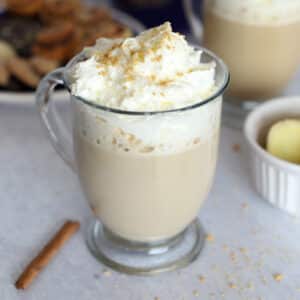 A cup of ginger latte topped with whipped cream with a cinnamon stick.