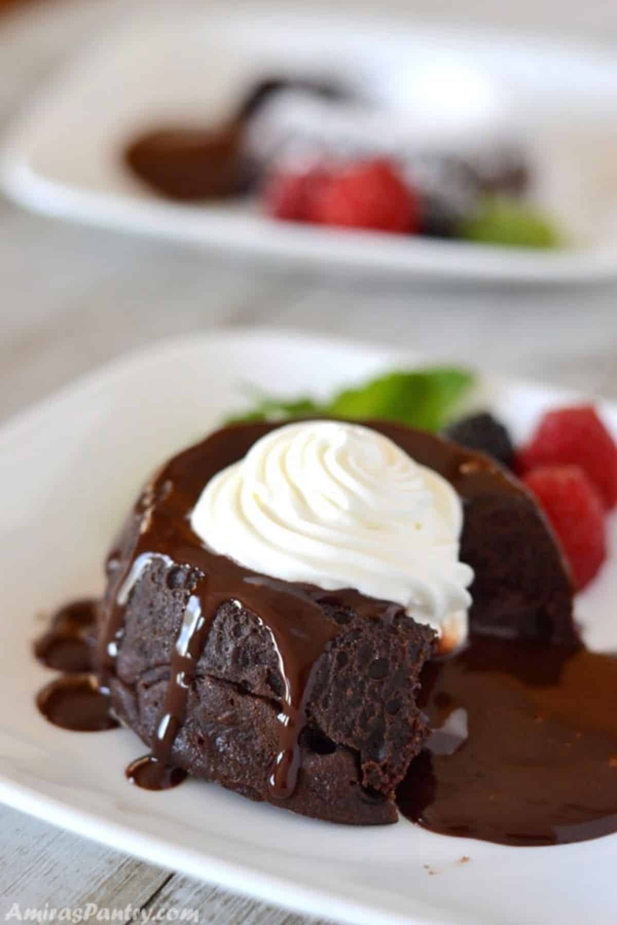 A close up of a piece of chocolate cake on a plate, with Cream on top.