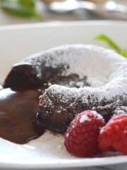 Chocolate lava cake on a white plate dusted with powdered sugar.