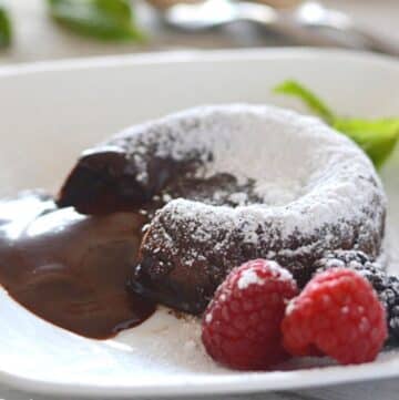 Chocolate lava cake on a white plate dusted with powdered sugar.