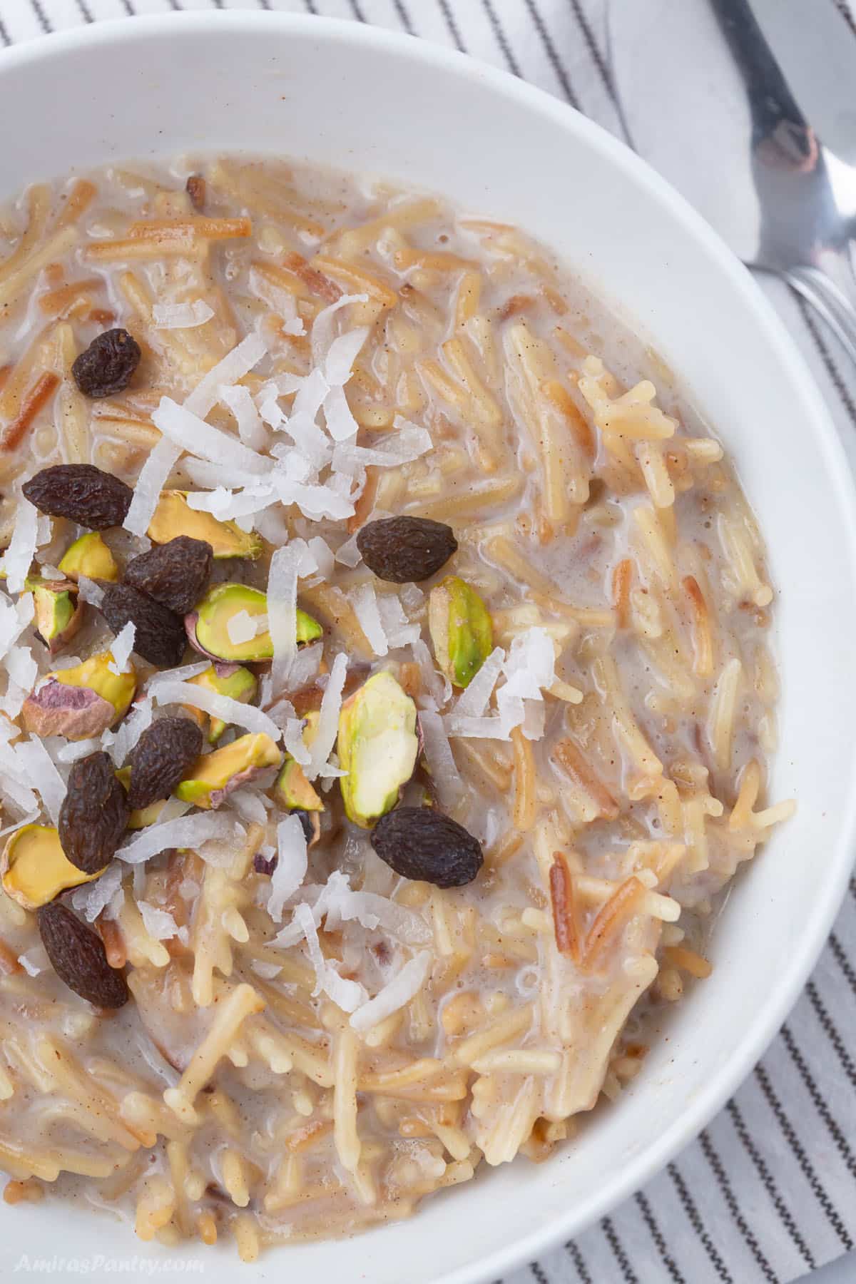 A white bowl with sweet vermicelli  garnished with nuts.