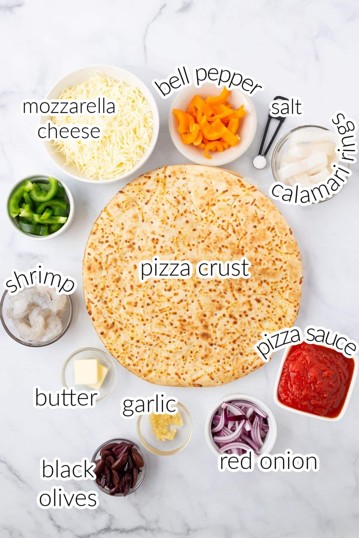 Seafood pizza ingredients on a marble surface.