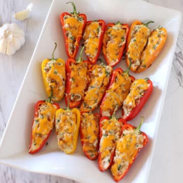 A white serving platter with stuffed sweet peppers.