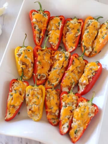 A white serving platter with stuffed sweet peppers.