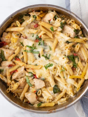 A top view of a skillet with creamy tuscan chicken pasta.