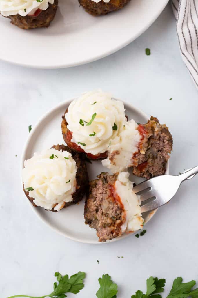 3 meatloaf cupcakes on a white plate with a fork.