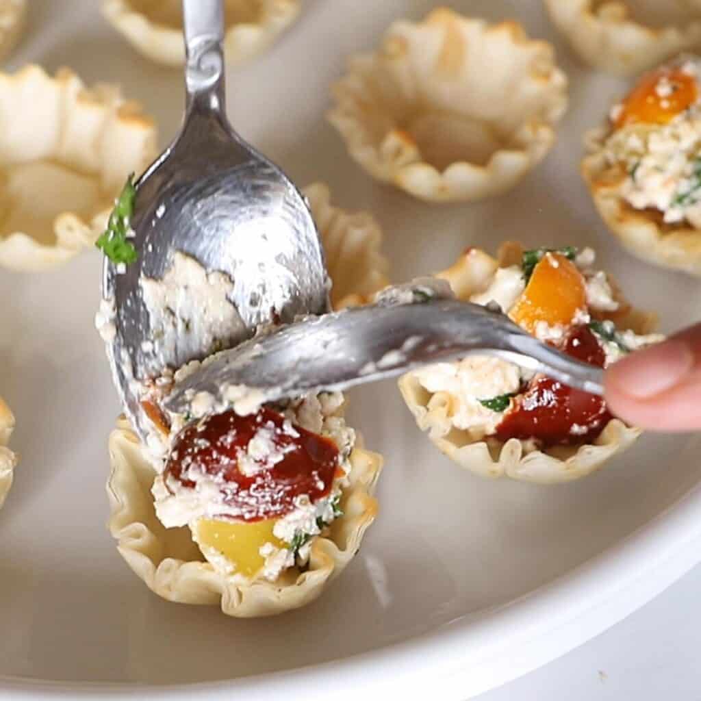 Stuffing the phyllo shells with cheese mix.