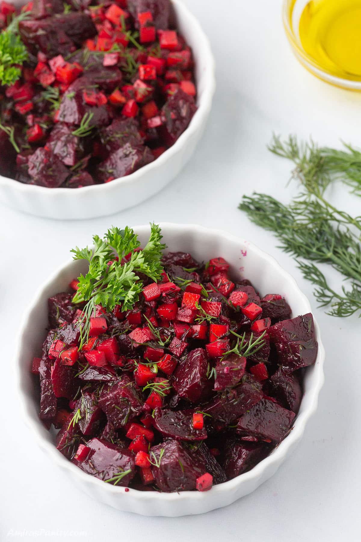An overhead view of two white bowls of beet salad.