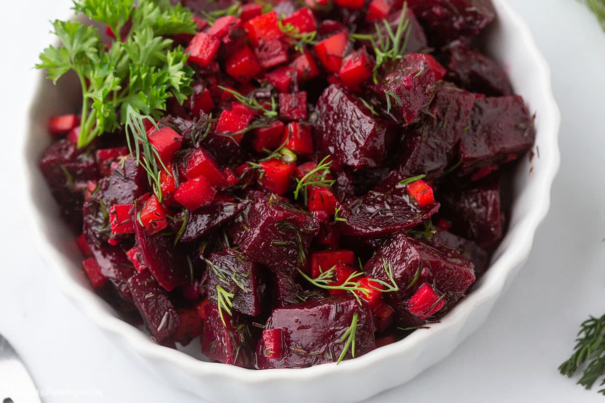 A small white serving bow with beet and carrot salad.