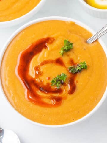 A top view of a white bowl filled with Turkish red lentil soup.