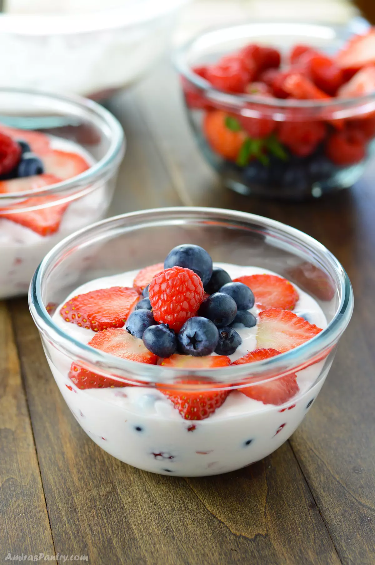 A close up look at a bowl of creamy fruit salad on a wooden surface.