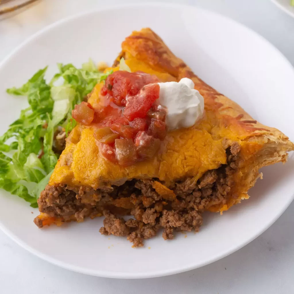A piece of taco crescent pie on a white plate.