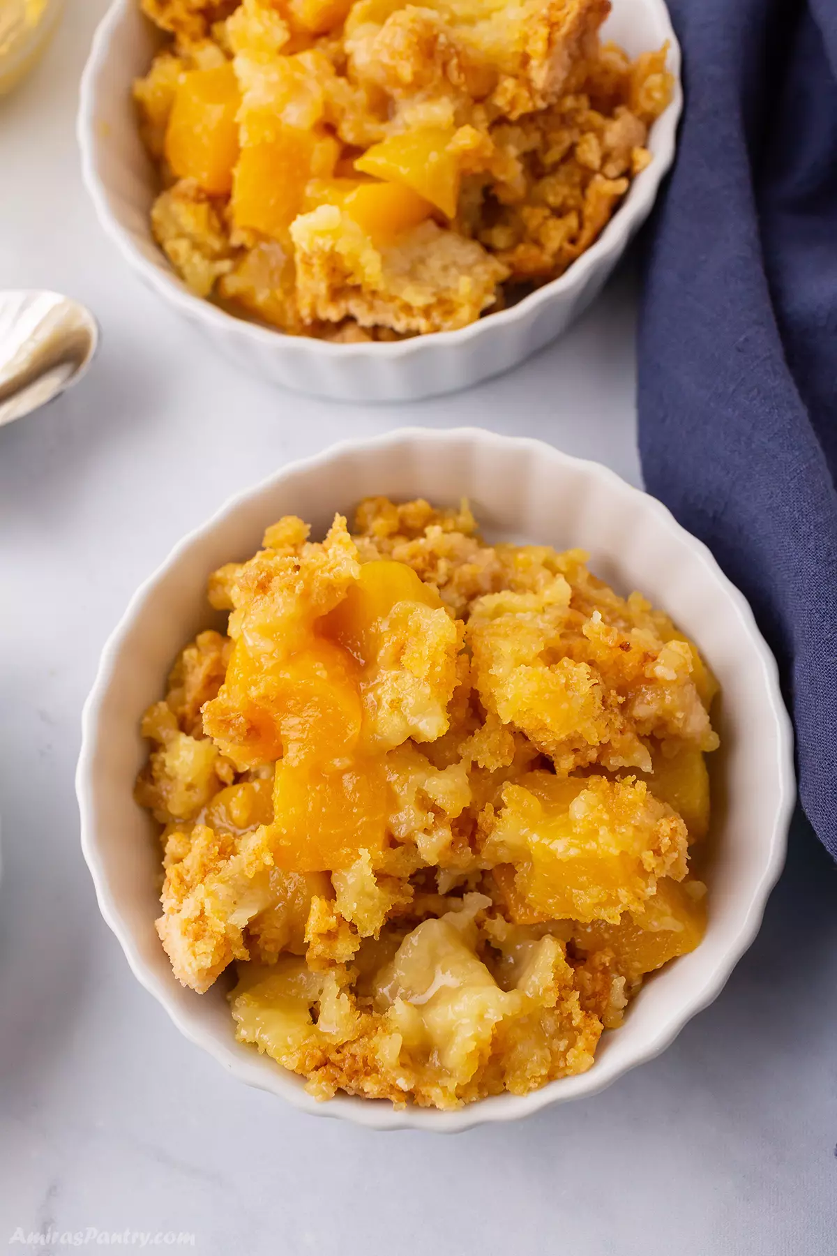 Two small serving bowls of peach cobbler.
