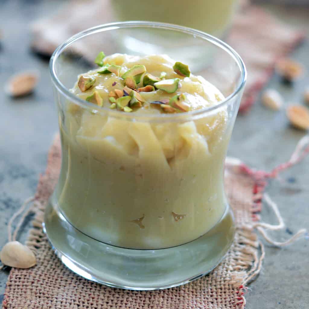 Fresh homemade pistachio pudding in a cup garnished with pistachios.