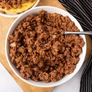 A white deep bowl with seasoned ground beef.