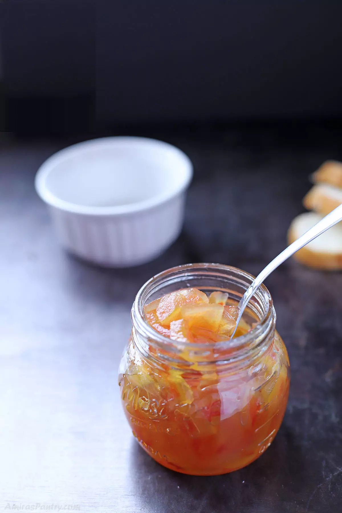 A spoon scooping some watermelon rind preserves from a jar.
