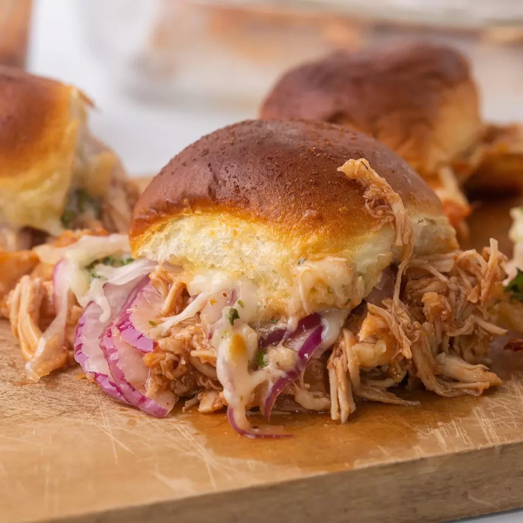 A close up image of a chicken slider on a wooden cutting board.