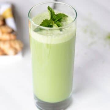 Mint matcha smoothie in a tall glass garnished with fresh mint leaves.