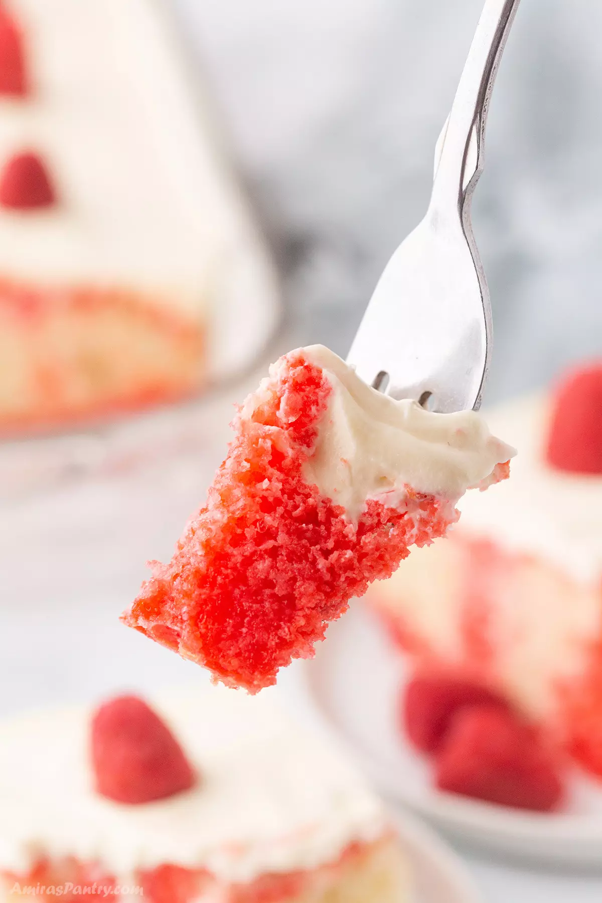A fork with a piece of raspberry poke cake .