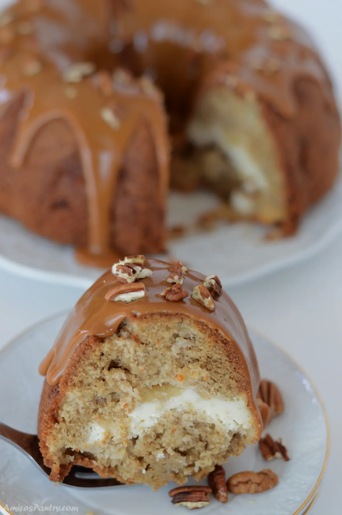 A close up of a slice of apple cream cheese bundt cake on a white dessert plate.