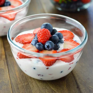 A close up image of a bowl with creamy fruit salad.