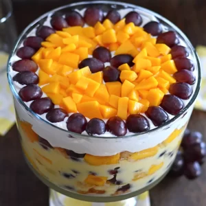 A top view of a fruit trifle dish with mango slices and grapes.