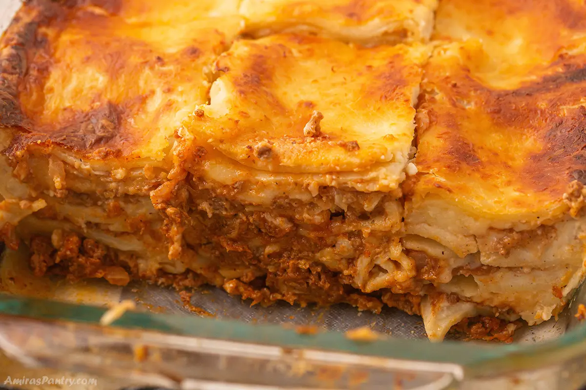A close up look at a lasagna dish with slices cut up to show layers.
