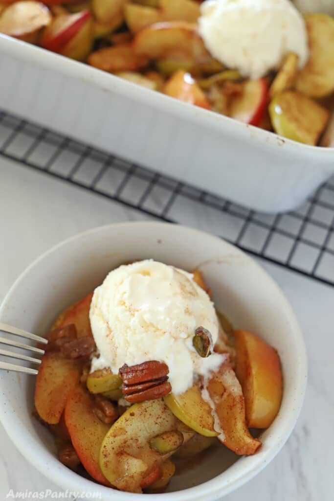 A small serving bowl of baked apple slices topped with ice cream.