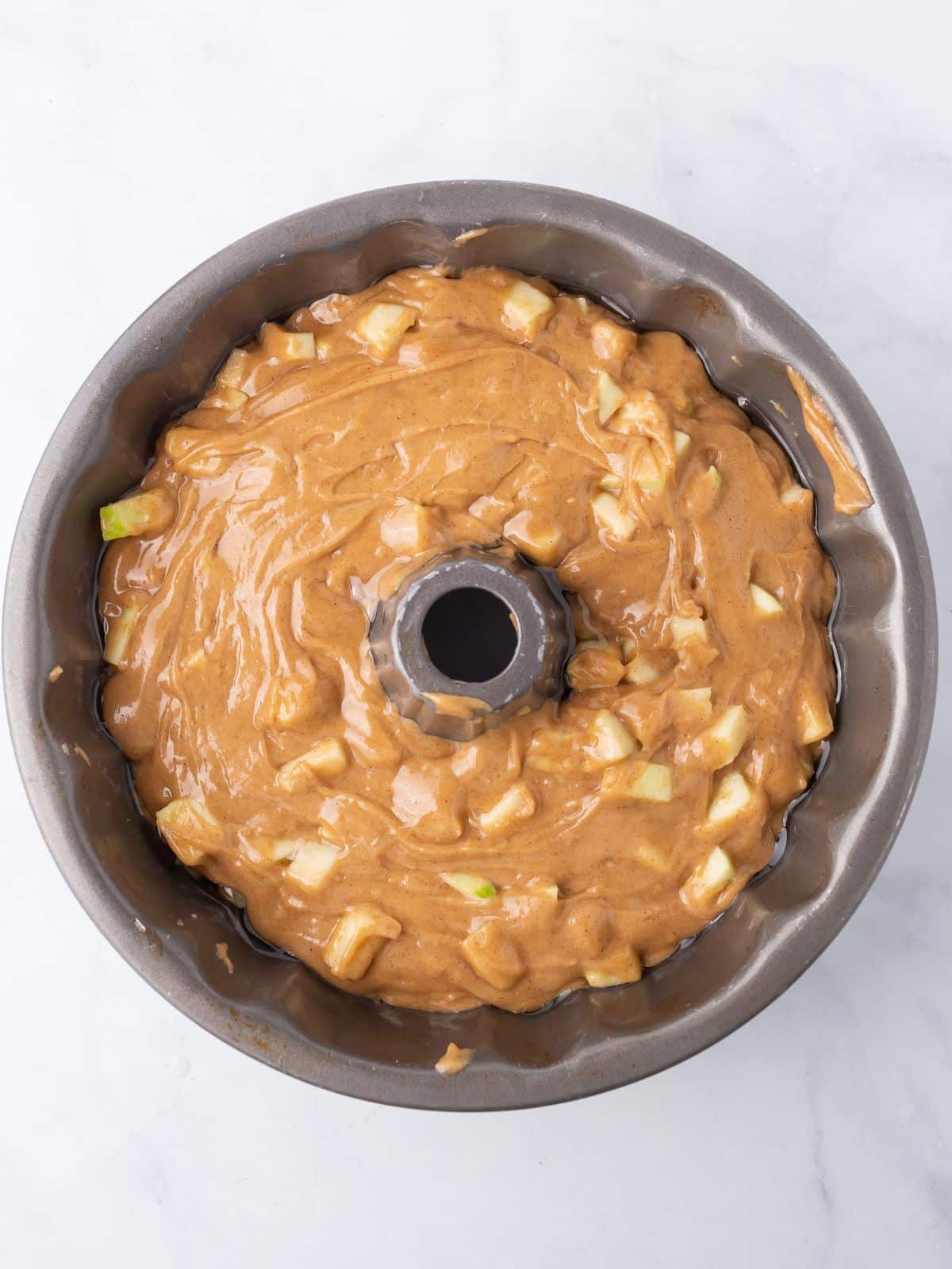 Apple cake in a bundt pan ready to be baked.