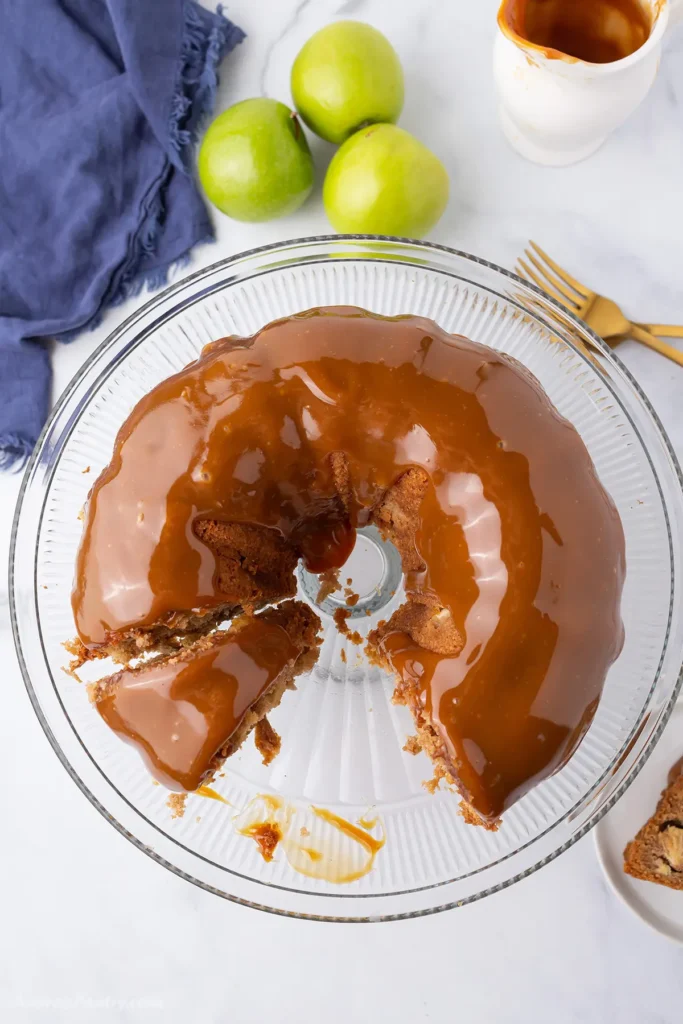 Apple bundt on a serving plate with a slice taken away.