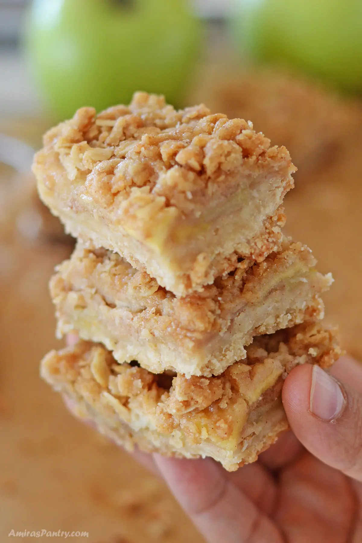 A hand holding a stack of apple crisp bars.