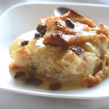A piece of bread pudding on a white dessert plate.
