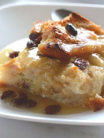 A piece of bread pudding on a white dessert plate.