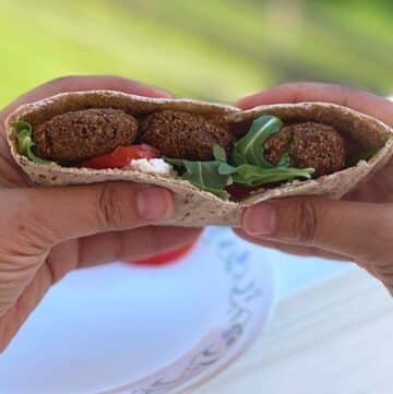 Hands holding a falafel sandwich.