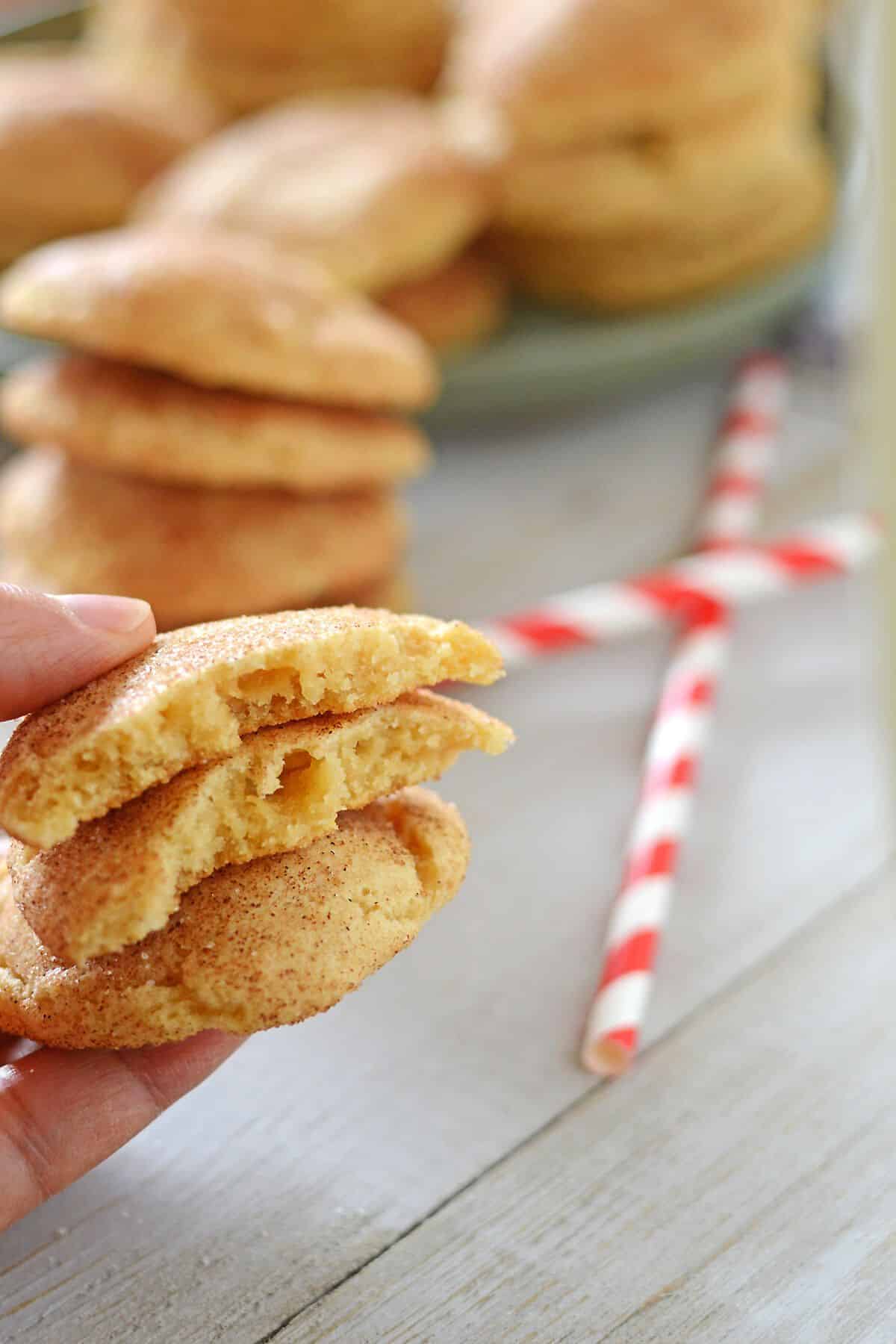 A hand holding a stack of snickerdoodle cookies to show texture.