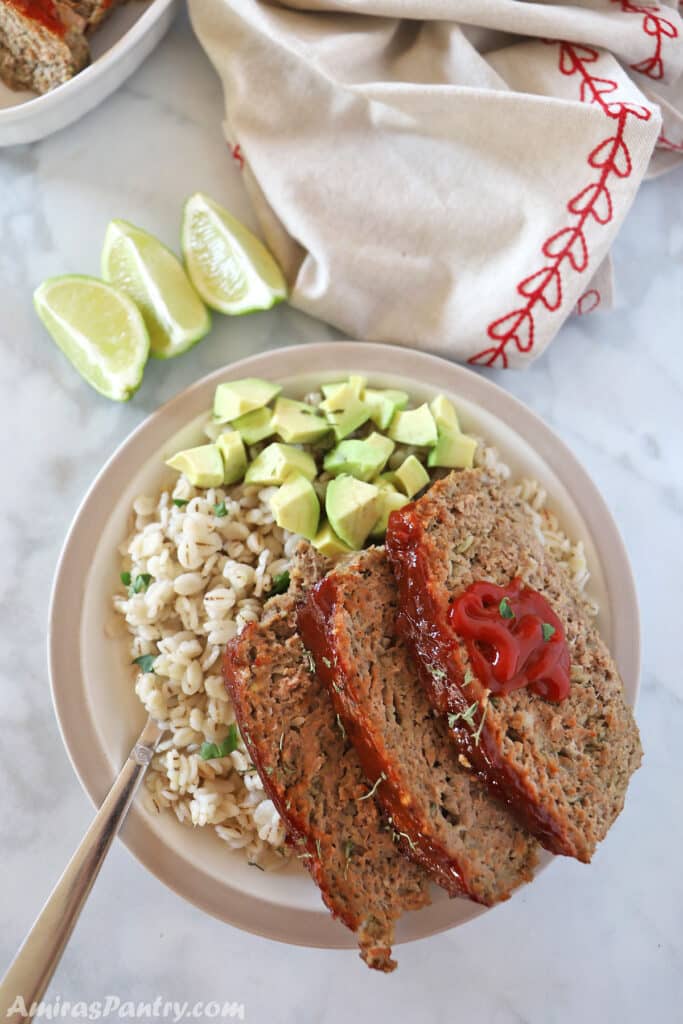 Turkey meatloaf slices on a plate with diced avocados.