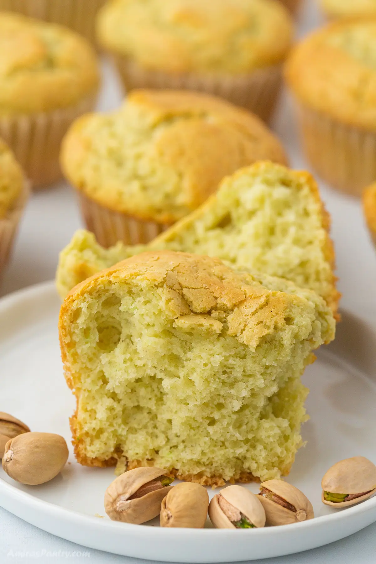 A pistachio muffin on a small plate cut open to show texture.