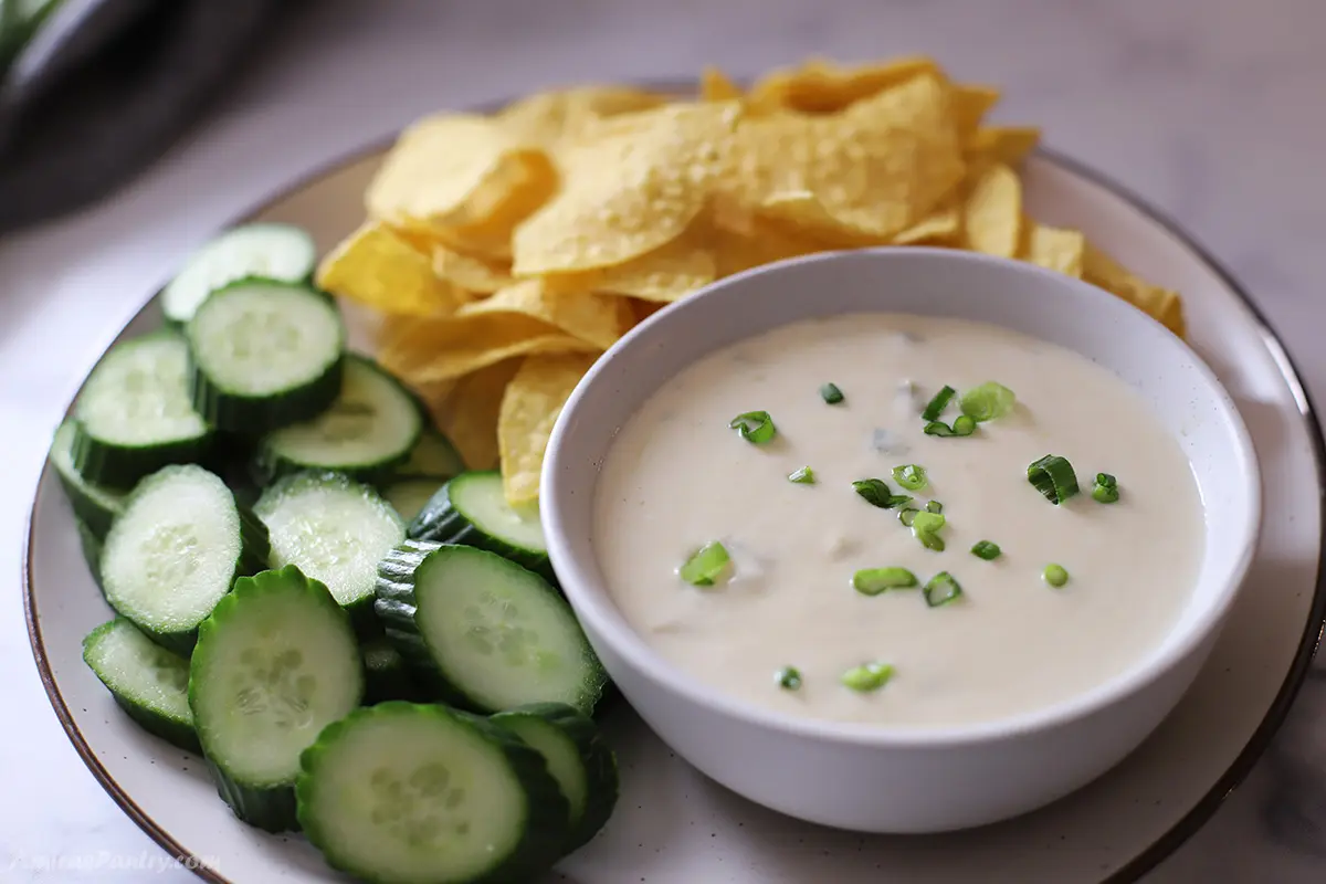 Sour cream sauce on a bowl garnished with chopped green onion.