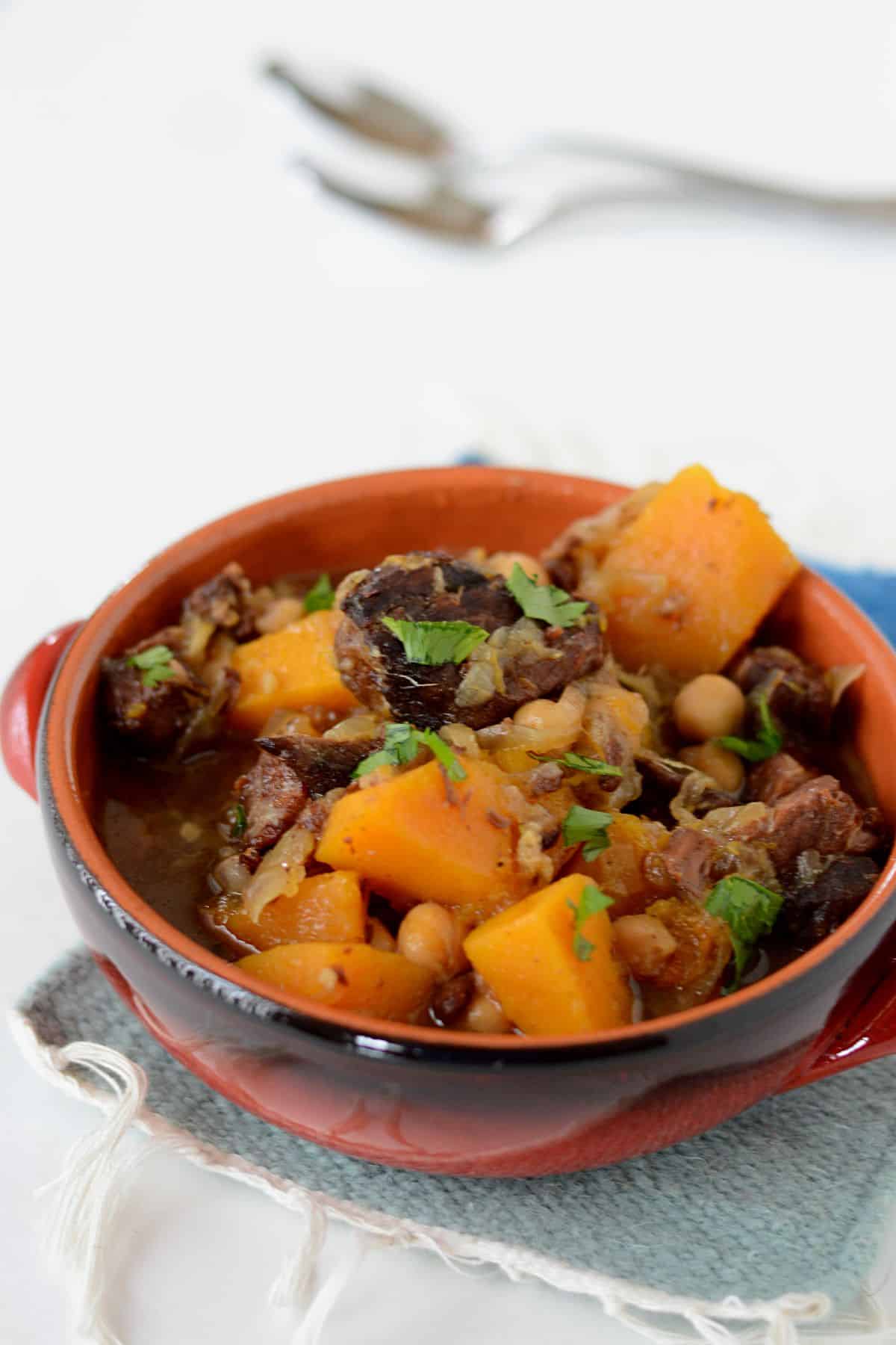 A top view of a red bowl with Moroccan beef tagine with butternut squash.