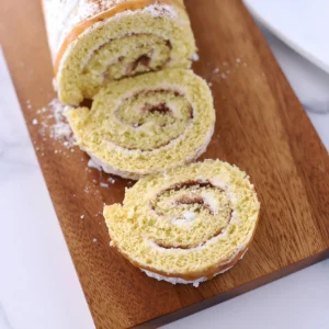 Two cinnamon swiss roll slices on a cutting board.