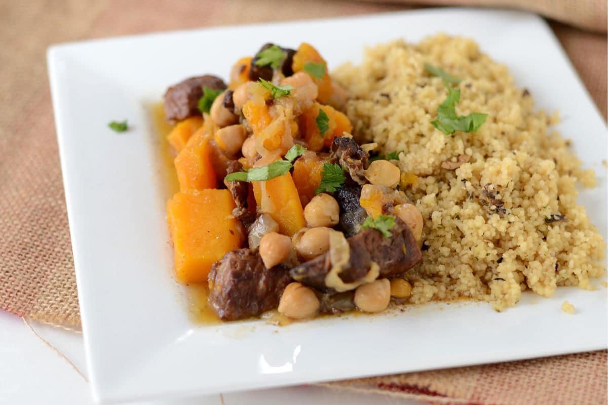 Beef with butternut squash with couscous on a white plate.