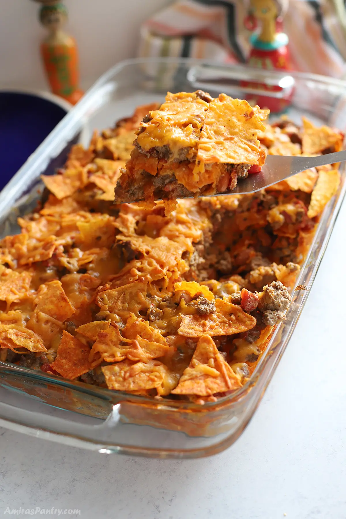 A serving spoon scooping a portion of the doritos casserole.