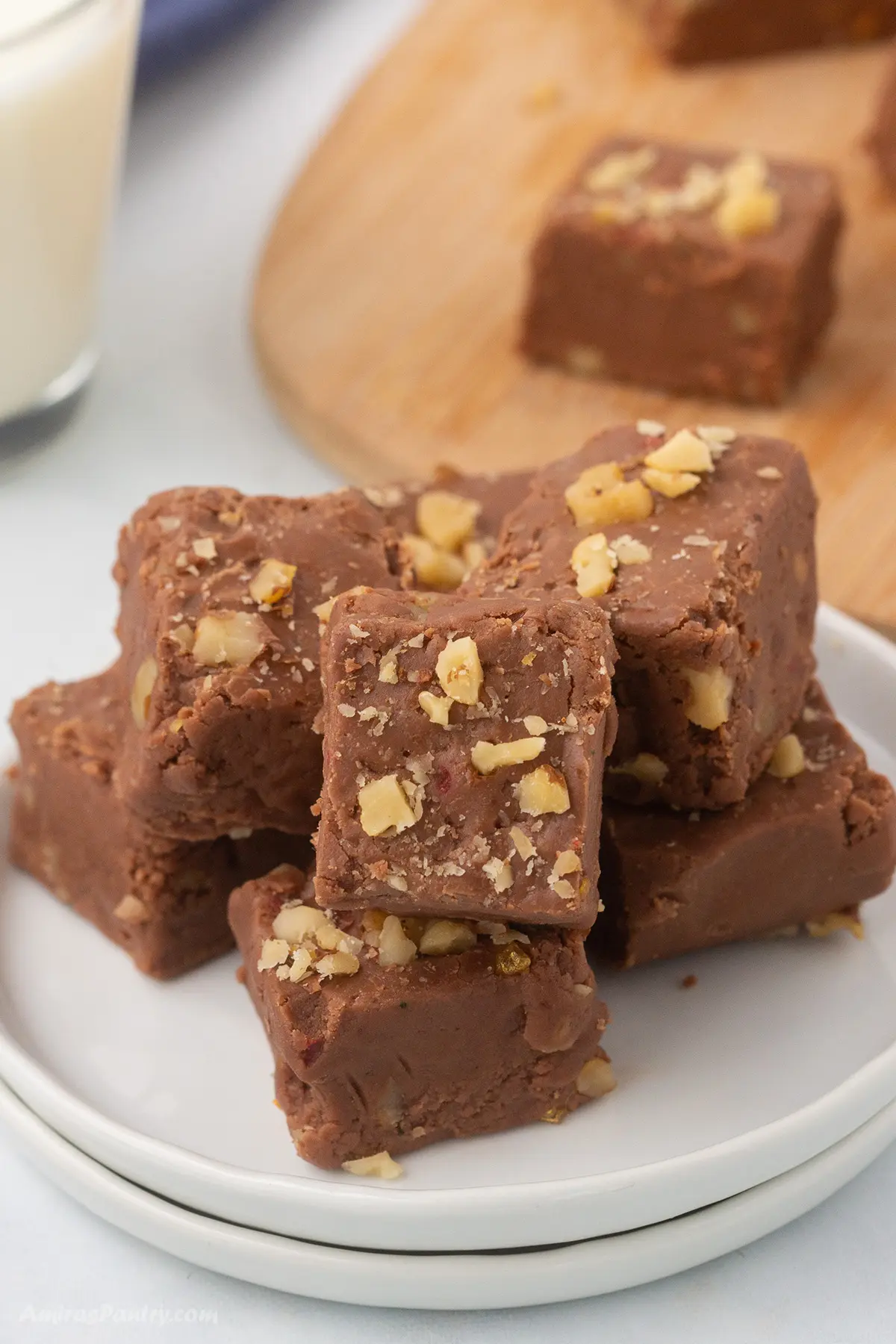 Fudge garnished with walnuts on small white plates.