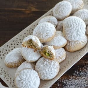 Egyptian Kahk cookies dusted with powdered sugar and placed on a white platter.
