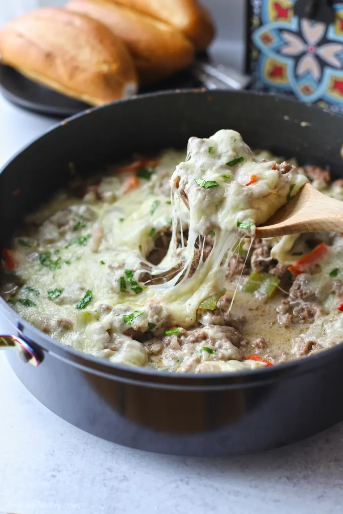 A wooden spoon scooping some of the philly cheesesteak casserole.