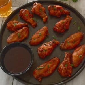 A top view of some bbq wings on a tray with sauce.